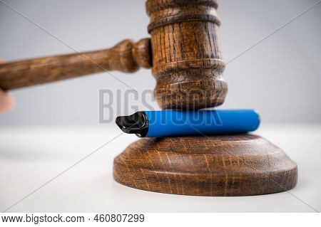 Judge Hammering Disposable Vape With Referees Gavel On White Table.