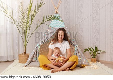 Smiling Satisfied Woman With Long Dark Hair Wearing White T Shirt Sitting In Peetee Tent With Her Ba