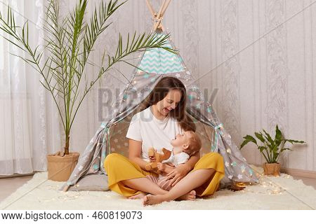 Image Of Happy Positive Joyful Woman With Dark Hair Wearing White T Shirt Sitting In Peetee Tent And
