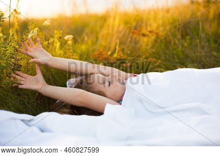 Girl Sleeps On Bed In Grass, Sweet Stretches And Yawns Sleepily, Good Morning In Fresh Air. Eco-frie