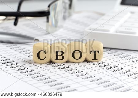 Wooden Cubes With The Word Cbot On Financial Background With Chart, Calculator, Pen And Glasses, Bus
