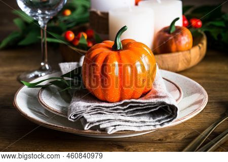 Table Setting With Plate, Pumpkin And Candles At Wooden Table. Autumn Table Decorations. Thanksgivin