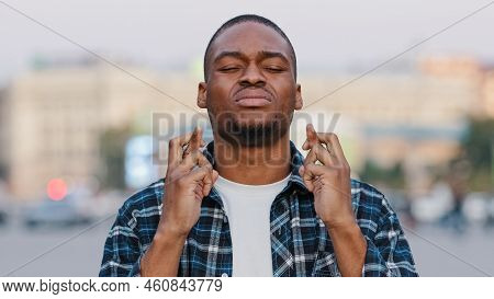 African American Young Hopeful Man Stands In City On Street Crossing Fingers Praying Says Prayer Hop