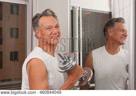 Mature Man 60plus Working Out With Weights At Home In Front Of A Mirror Doing Bicep Curls