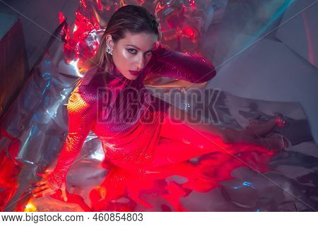 Portrait Of A Young Beautiful Woman In A Stylish Scarlet Dress On A Shimmering Silver Background, Ir