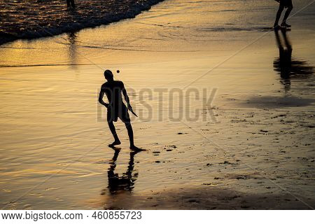 Young People Playing Frescoboll Against Sunset At Beach