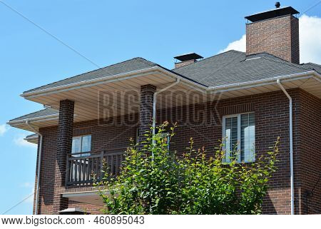 Brick House With Asphalt Shingles Roof, Chimney, Balcony, Rain Gutter Pipeline And Soffit Boards. Cl