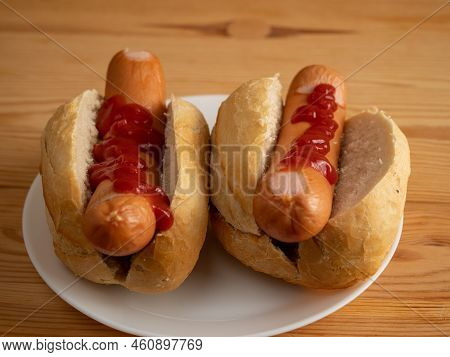 Boiled Sausage With A Bun On A Wooden Background.