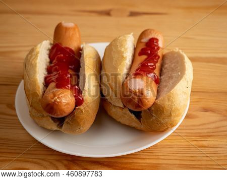 Boiled Sausage With A Bun On A Wooden Background.