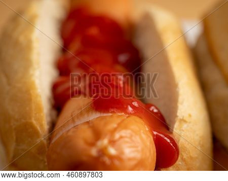 Boiled Sausage With A Bun On A Wooden Background.