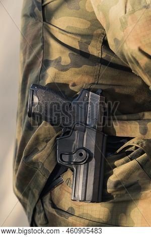 Vertical Close-up Shot Of Handgun In Holster Around Soldiers Waist. Camouflage Army Uniform. . High 