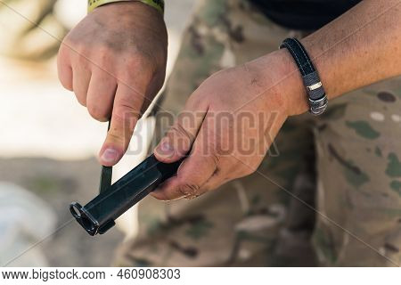 Gunsmithing Concept. Two Hands Of An Unrecognizable Caucasian Man In Moro Pants Showing A Black Part