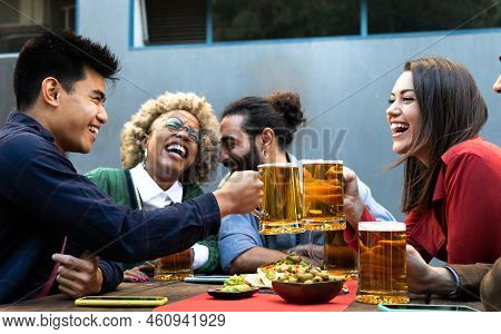Cheers. Multiracial Group Of Happy And Smiling Friends Toast With Beer And Laugh Together In A Bar O