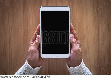 Mature Female Hands Holding The White Tablet Pc Computer With Blank Screen Isolated On Desk Backgrou