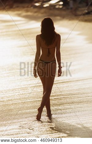 Silhouette Of A Beautiful Brunette Girl Against The Beach In Sunset Light. Lonely Woman Model With P