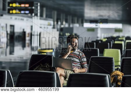 Lonely Man Sit Down And Use Technology Device Like Laptop And Mobile Phone At The Airport Gate Waiti