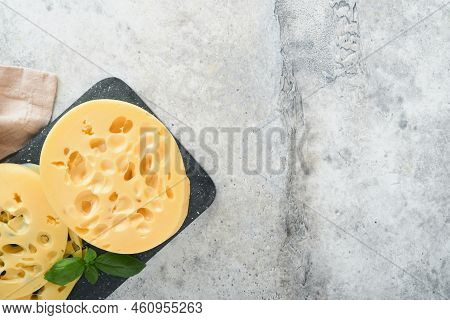 Cheese Maasdam Or Radamer. Piece Of Cheese On Black Marble Or Stone Standa On Old Grey Concrete Back