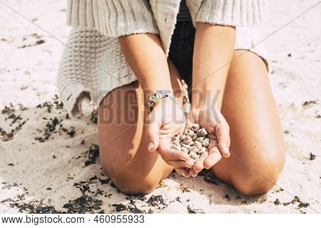 Caucasian Woman On The Sand At The Beach Holding And Showing A Lot Of Little Marine Shells Under The