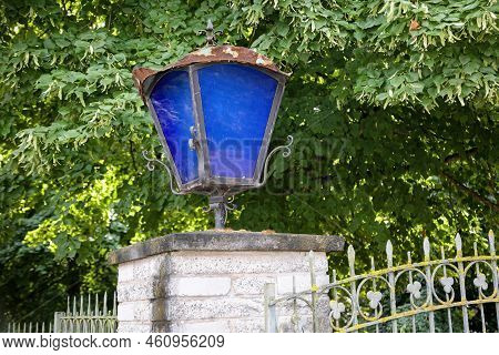 A Lantern With Blue Discson A Gatepost.