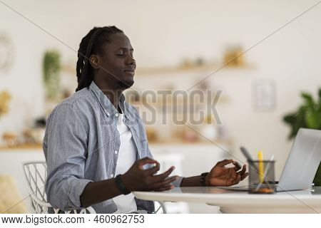 Zen Concept. Portrait Of Young Black Male Sitting At Desk And Meditating