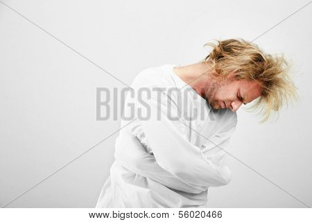 Mentally ill man in strait-jacket on gray background