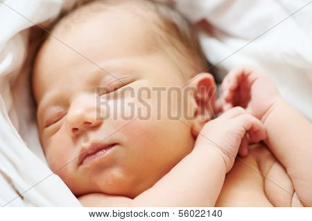 Close-up newborn baby sleeping in white bedsheet