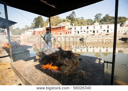 KATHMANDU, NEPAL - DEC 3: Unidentified local people during the cremation ceremony along the holy Bagmati River in Bhasmeshvar Ghat at Pashupatinath temple, Dec 3, 2013 in Kathmandu, Nepal.