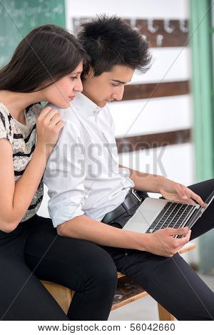 Two students studying from a laptop computer in schoolroom