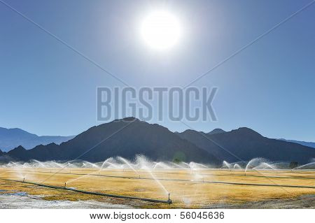 Irrigation Sprinklers Water A Dry Field By Mountains