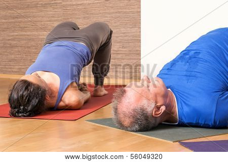 An image of some people doing yoga exercises - Setu Bandha Sarvangasana 