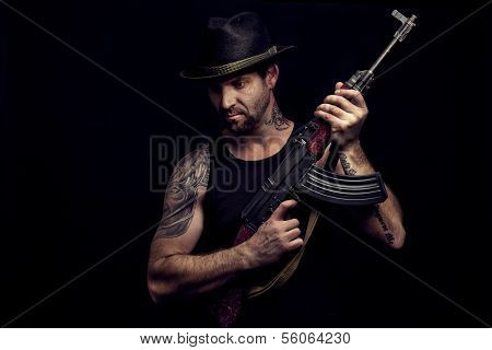 Low Key Portrait Of Gangster With Hat And Maschine Gun In The Darkness.