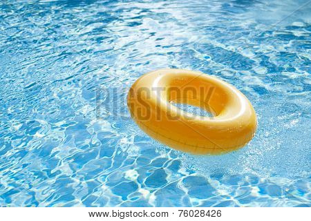 floating ring on blue water swimpool with waves reflecting in the summer sun