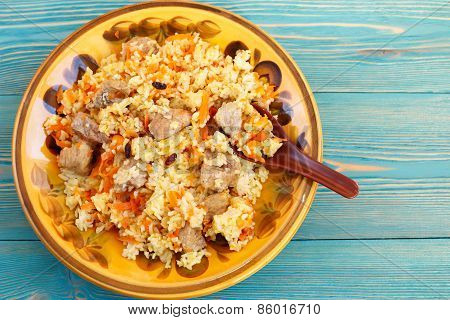 Traditional oriental pilaf, rice with meat and carrot on blue desk