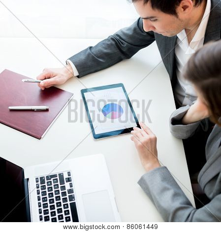 Businessman And Businesswoman, Analysing A Statistical Business Pie Graph On A Tablet Computer