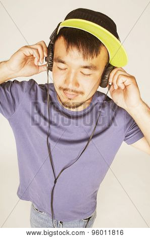 young asian man in hat and headphones listening music on white background