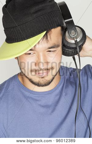 young asian man in hat and headphones listening music on white background