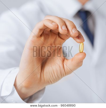 picture of doctor hand showing one capsule