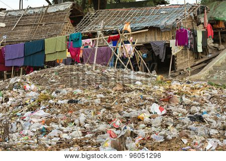 Laundry drying under a large rubbish pile in a slum area in Mandalay, Myanmar