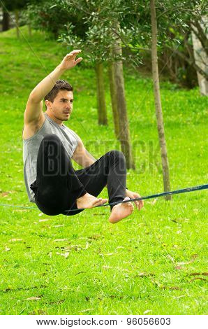 Man sitting on tightrope in park environment