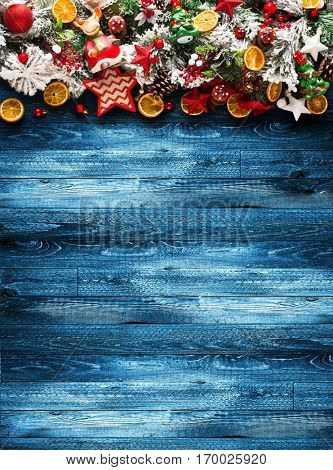 Merry Christmas Frame with green pine, colorful baubles, knots with berries,stars, orangesand other seasonal stuff over an old wooden aged background