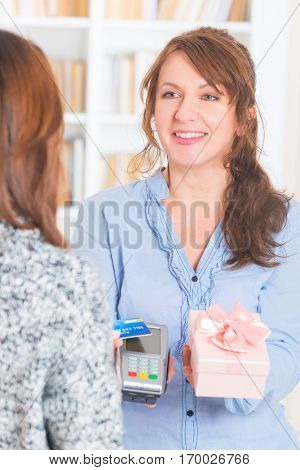 Woman making contactless payment for a gift with credit or debit card on wireless payment terminal
