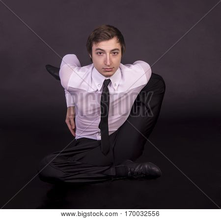 Extraordinary gymnast on a black background. The man with no bones. Studio photography of circus performers..