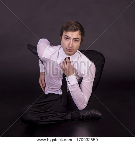 Extraordinary gymnast on a black background. The man with no bones. Studio photography of circus performers..