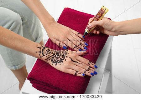 Woman applying henna on female hand