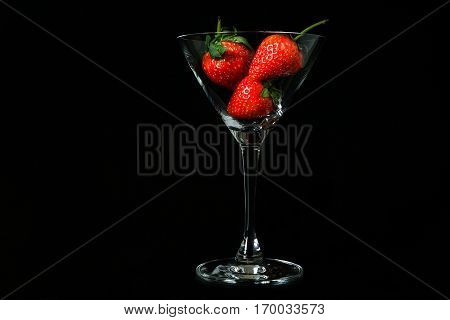 strawberry in glass on black background isolated