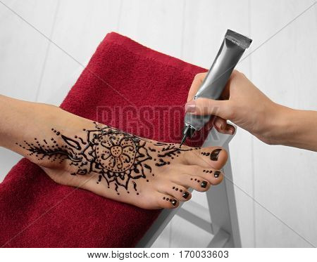 Woman applying henna on female foot