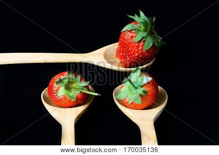 strawberry in wooden spoon on black background isolated