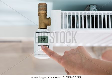 High Angle View Of Person Hand Adjusting Temperature On Thermostat