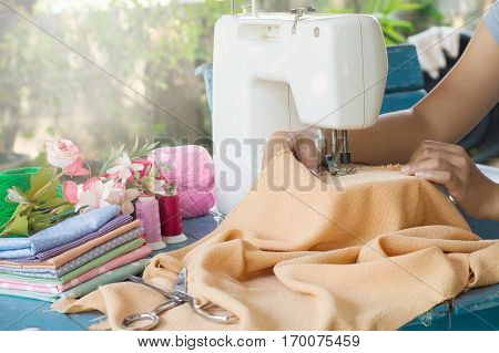 Tailor working on a sewing machine with orange fabric
