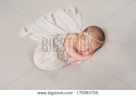 lovely smiling sleeping infant wrapped in gray warm diaper